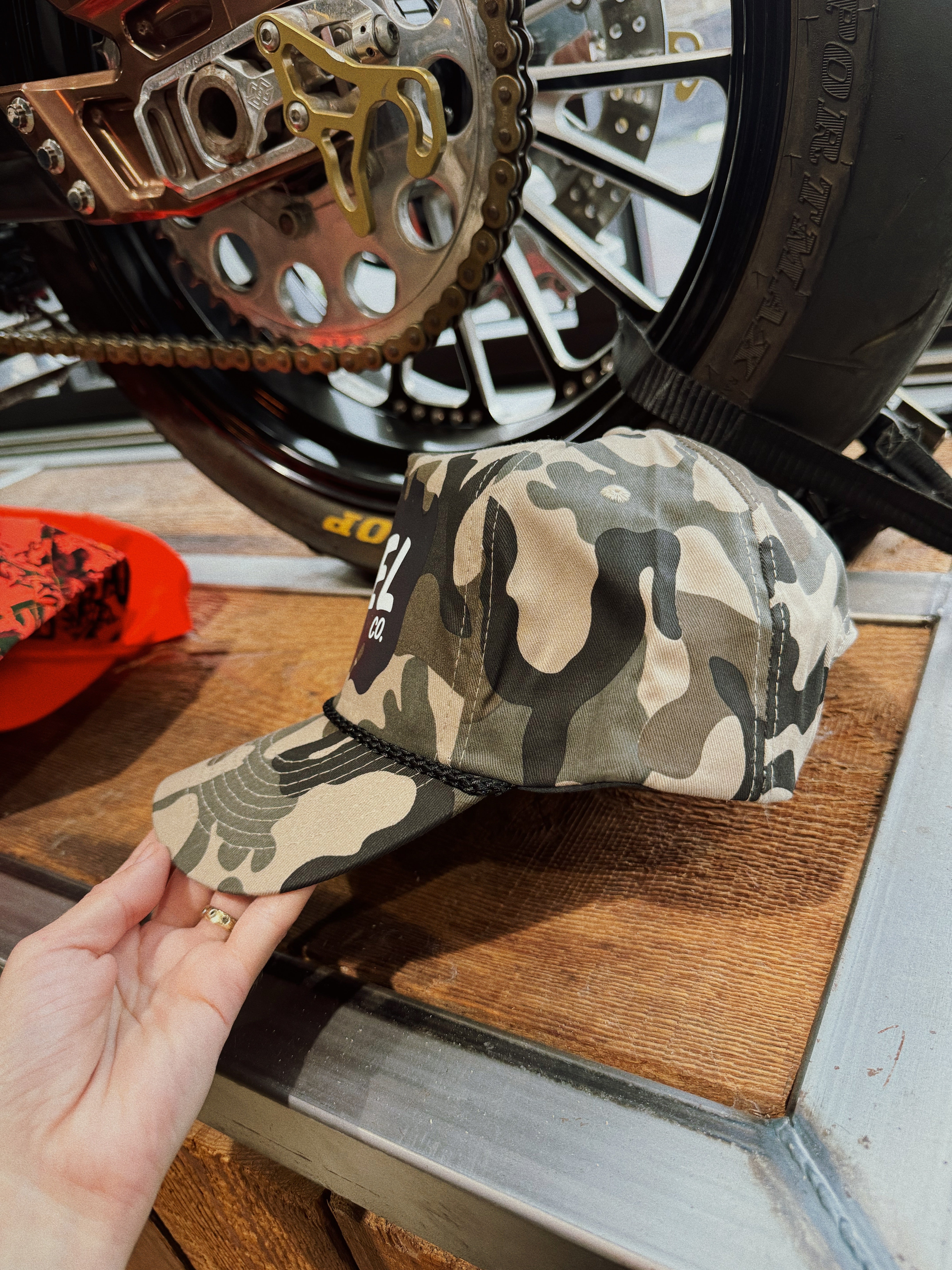 A camo snapback hat with the Axel Co. logo on the front