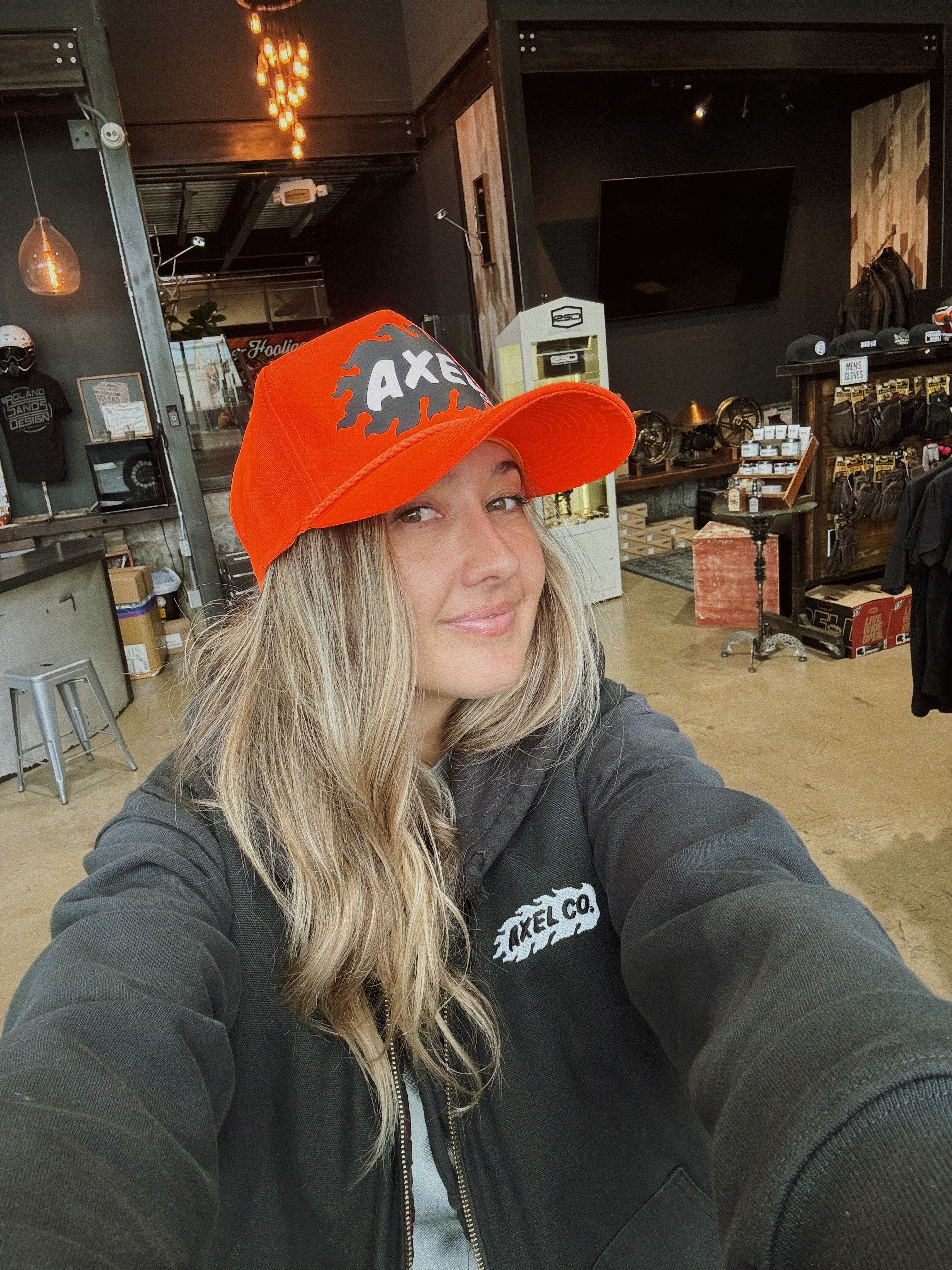 A orange snapback hat with the Axel Co. logo on the front