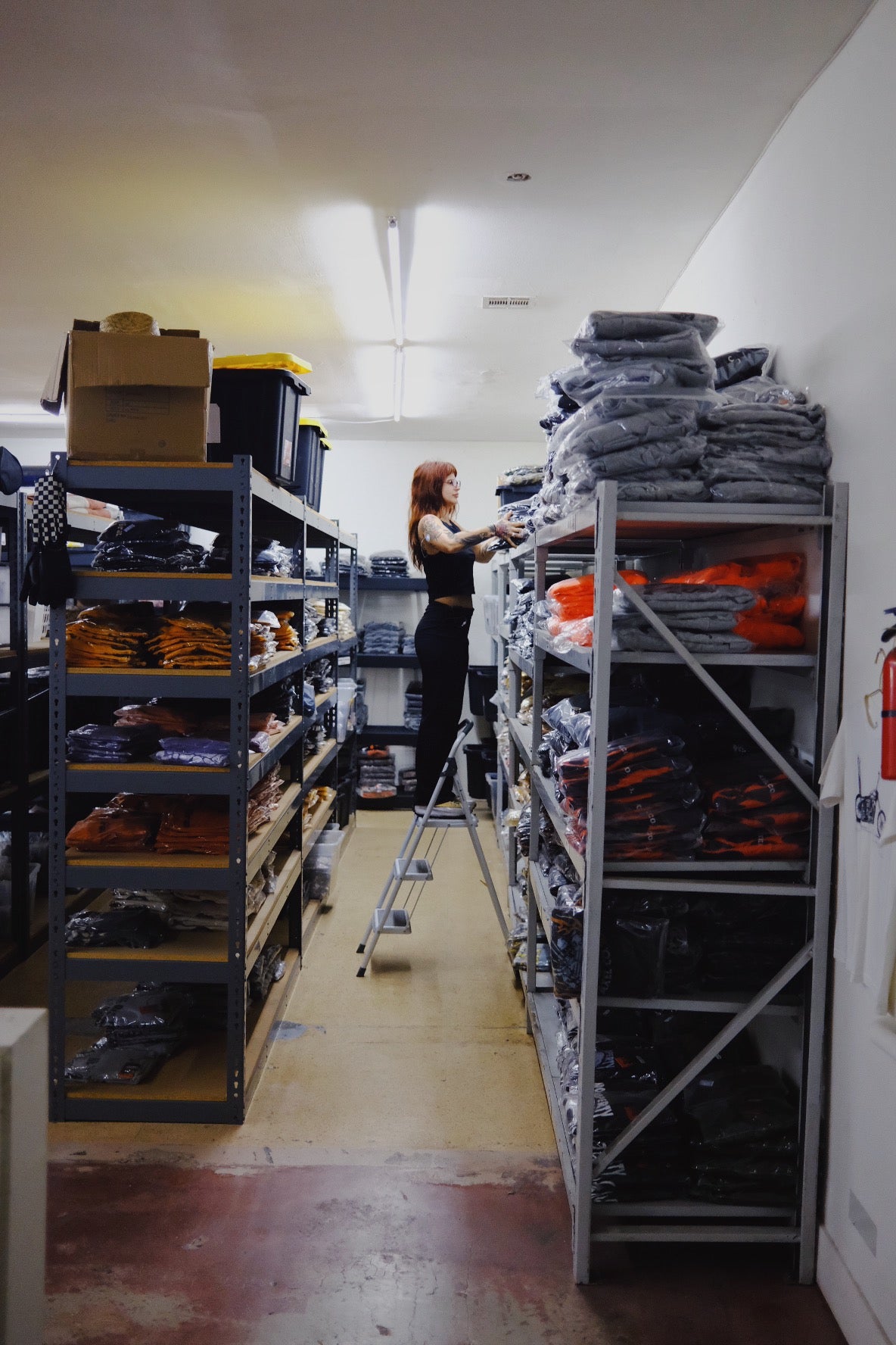 Person using a ladder to organize items on shelves in a warehouse setting